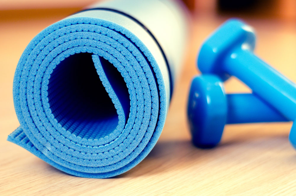 A rolled up yoga mat and some hand weights.
